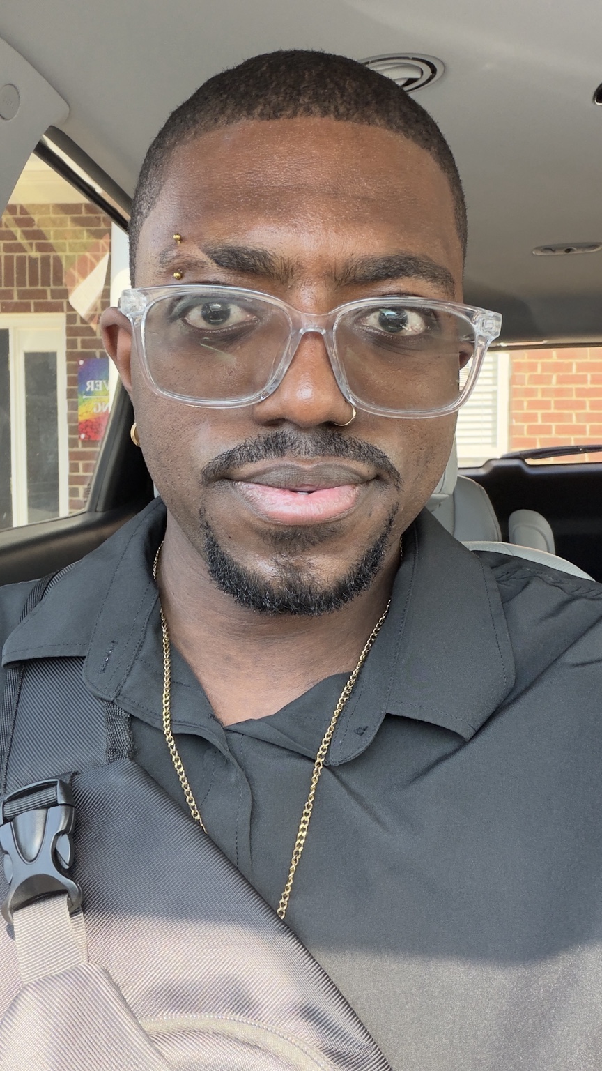 A close-up of Napoleon B’Myte in clear glasses and a black shirt